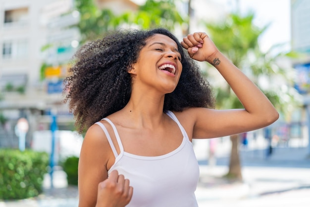 Una joven afroamericana al aire libre celebrando una victoria