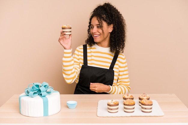 Joven afroamericana aprendiendo a hacer muffins y pasteles dulces