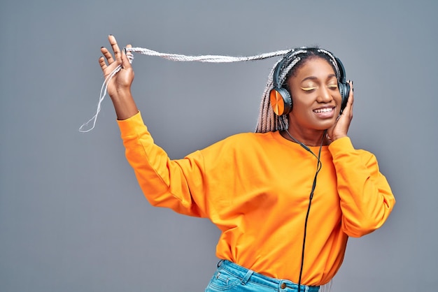 Joven afroamericana bailando y escuchando música con auriculares Copiar espacio