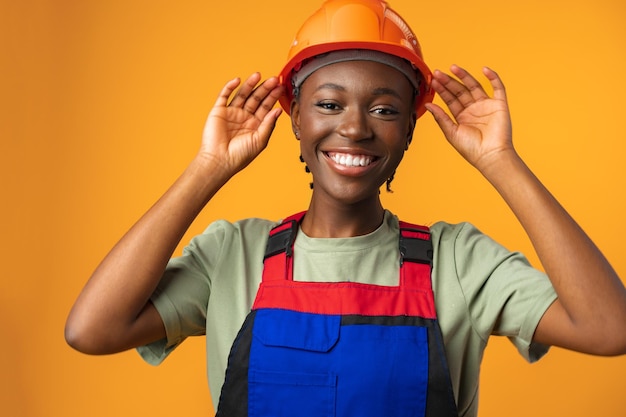 Joven afroamericana con casco de arquitecto contra el fondo amarillo