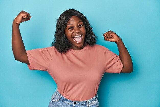 Joven afroamericana con curvas mostrando gesto de fuerza con brazos símbolo de poder femenino