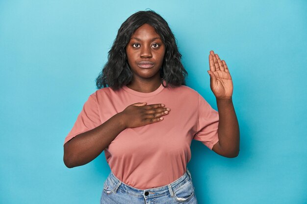 Joven afroamericana con curvas prestando juramento poniendo la mano en el pecho