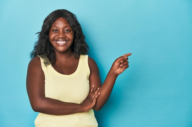 Joven afroamericana con curvas sonriendo alegremente señalando con el dedo índice