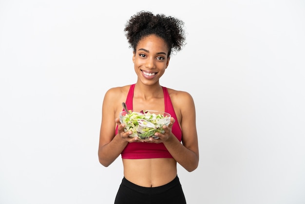 Joven afroamericana con ensalada aislado sobre fondo blanco sosteniendo un plato de ensalada con expresión feliz