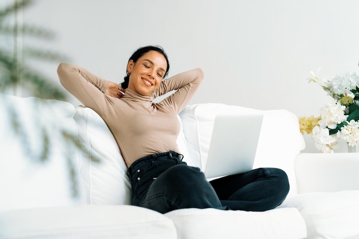 Foto joven afroamericana estirando los brazos para una relajación crucial en casa la mujer feliz pasando la mañana del fin de semana en la sala de estar