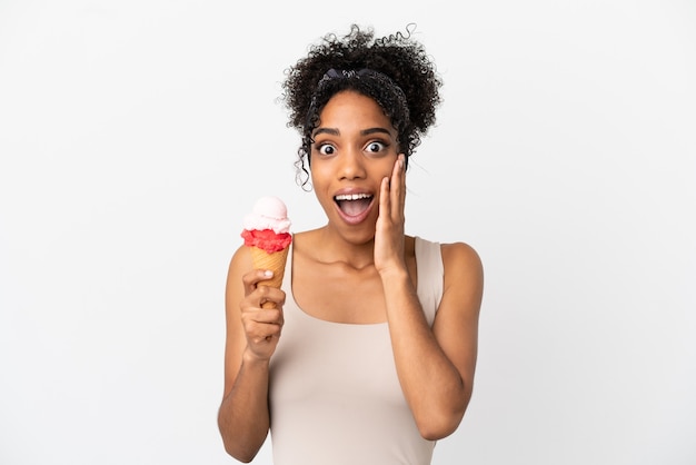 Joven afroamericana con un helado de cucurucho aislado sobre fondo blanco con sorpresa y expresión facial conmocionada