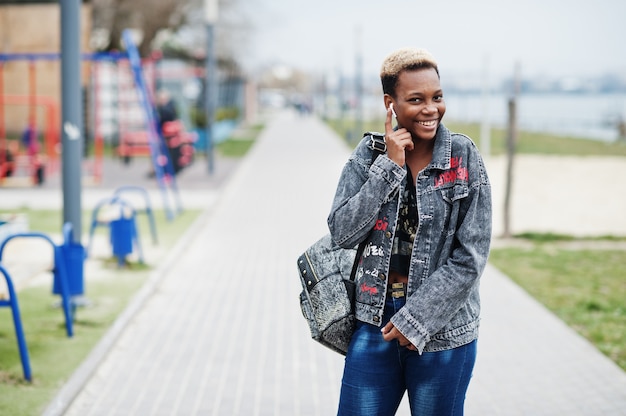 Joven afroamericana milenaria en la ciudad. Feliz mujer negra con auriculares inalámbricos. Concepto de generación Z