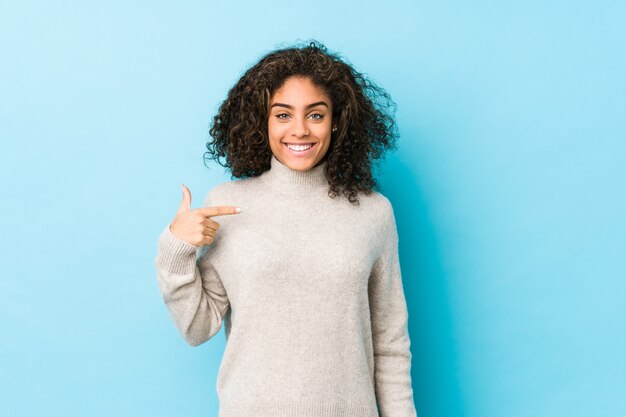 Joven afroamericana mujer de cabello rizado persona apuntando con la mano a una camisa copia espacio, orgulloso y confiado