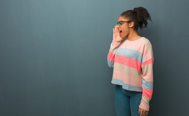 Joven afroamericana con ojos azules susurrando chisme bajo tono