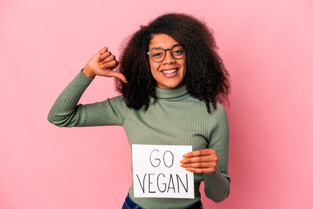 Joven afroamericana rizada sosteniendo un cartel vegano se siente orgullosa y segura de sí misma, ejemplo a seguir.