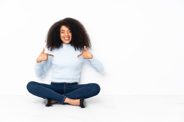 Joven afroamericana sentada en el suelo orgullosa y satisfecha de sí misma