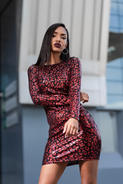 Joven afroamericana con un sexy vestido rojo cerca de un edificio