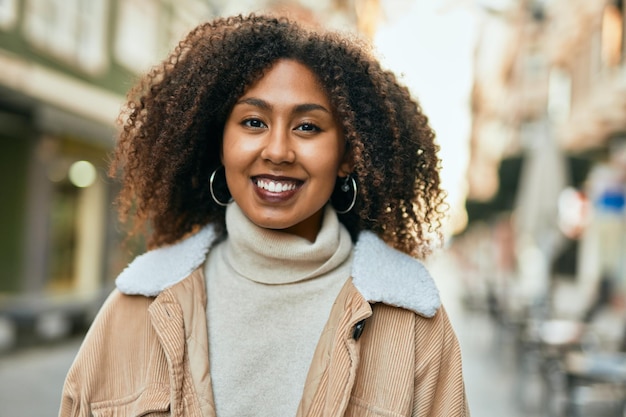 Joven afroamericana sonriendo feliz de pie en la ciudad