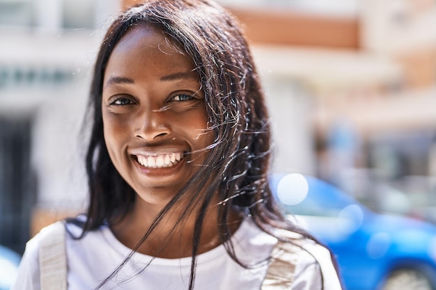 Joven afroamericana sonriendo segura de pie en la calle