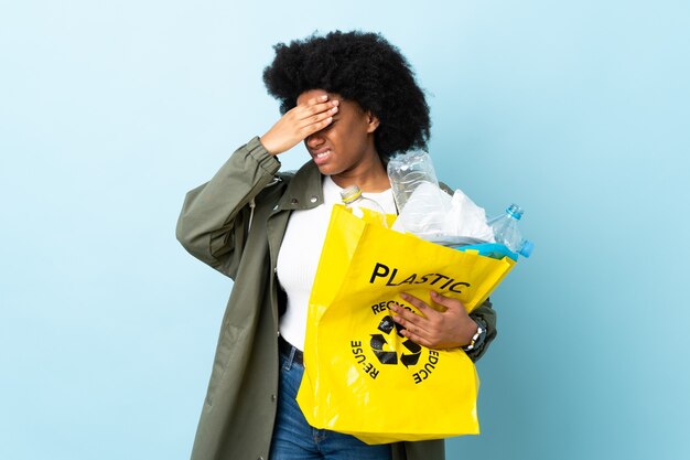 Joven afroamericana sosteniendo una bolsa de reciclaje con dolor de cabeza