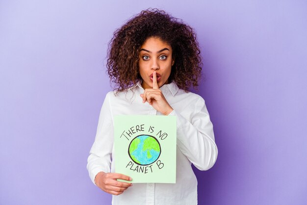 Joven afroamericana sosteniendo un cartel de No hay planeta B guardando un secreto o pidiendo silencio.