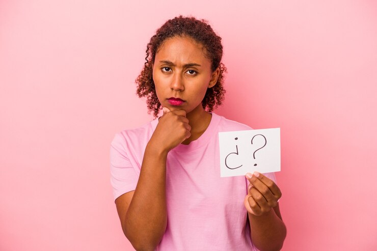 Foto joven afroamericana sosteniendo un cartel de pregunta aislado sobre fondo rosa