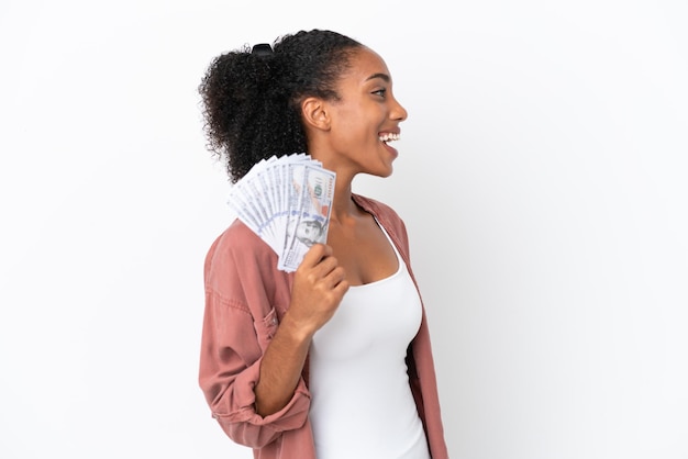 Joven afroamericana tomando mucho dinero aislada de fondo blanco riéndose en posición lateral