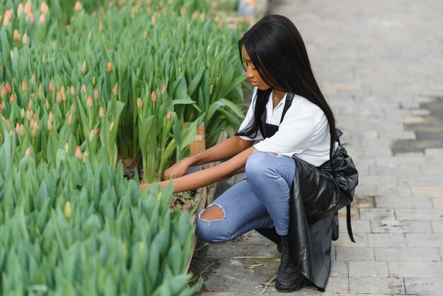 Joven afroamericana, trabajadora con flores en invernadero.