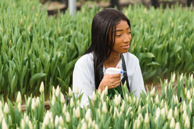 Joven afroamericana, trabajadora con flores en invernadero.