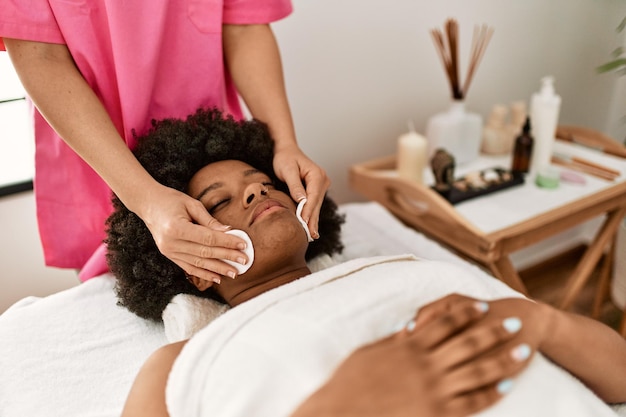 Joven afroamericana con tratamiento facial de limpieza en el centro de belleza