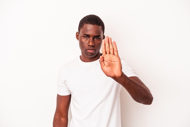 Joven afroamericano aislado de fondo blanco parado con la mano extendida mostrando la señal de alto, impidiéndote.