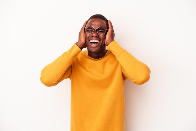 Joven afroamericano aislado de fondo blanco se ríe alegremente manteniendo las manos en la cabeza. concepto de felicidad.