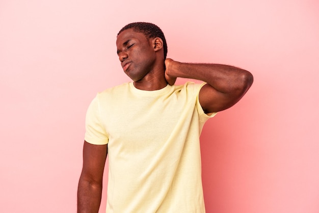 Joven afroamericano aislado de fondo rosa masajeando el codo, sufriendo después de un mal movimiento.