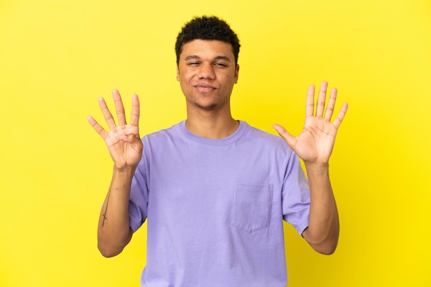 Joven afroamericano aislado sobre fondo amarillo contando nueve con los dedos