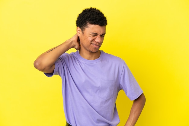 Joven afroamericano aislado sobre fondo amarillo con dolor de cuello