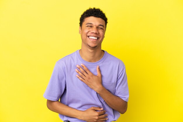 Joven afroamericano aislado sobre fondo amarillo sonriendo mucho