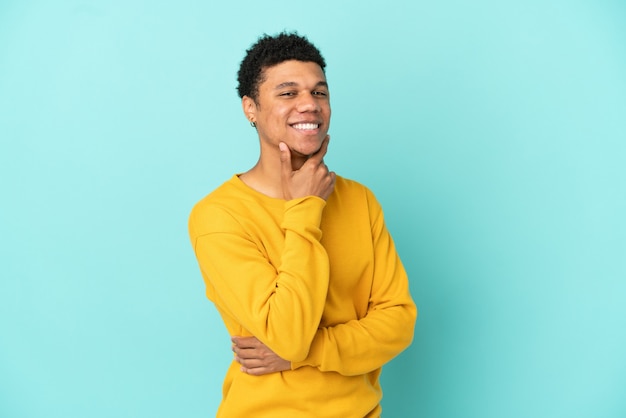 Joven afroamericano aislado sobre fondo azul feliz y sonriente