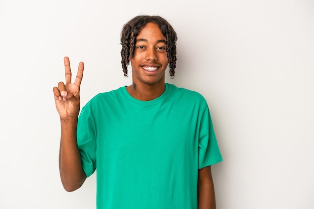 Joven afroamericano aislado sobre fondo blanco alegre y despreocupado mostrando un símbolo de paz con los dedos.