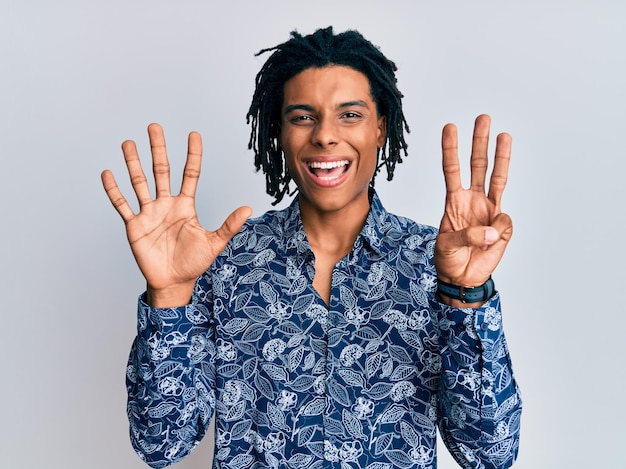 Joven afroamericano con camisa estilo años 80 que aparece y señala con los dedos número ocho mientras sonríe confiado y feliz