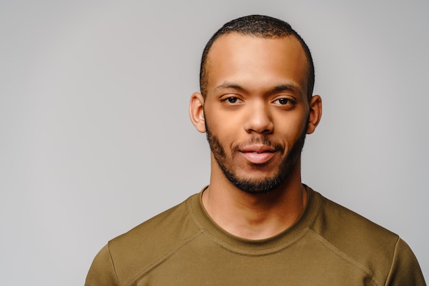 Joven afroamericano en camiseta verde sobre pared gris claro