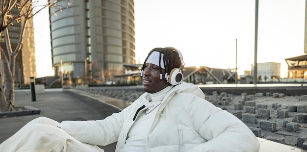 Joven afroamericano en la ciudad escucha música con auriculares