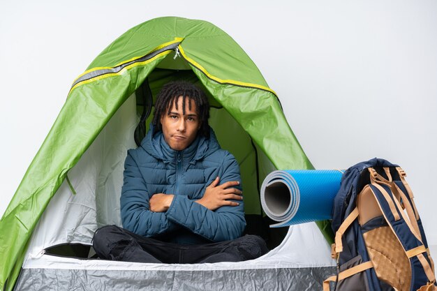 Joven afroamericano dentro de una tienda de campaña verde sintiéndose molesto