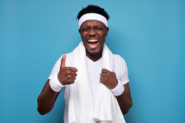 Joven afroamericano después de entrenar con toalla blanca mostrando el pulgar hacia arriba