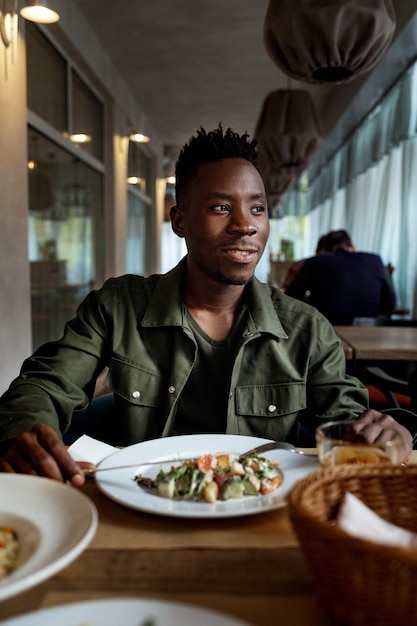 Joven afroamericano está comiendo en un restaurante