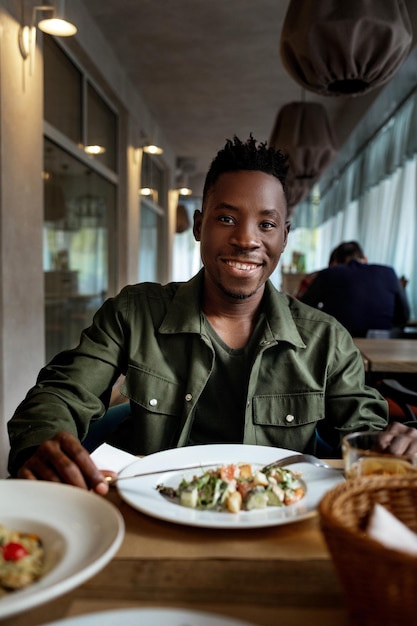 Joven afroamericano está comiendo en un restaurante