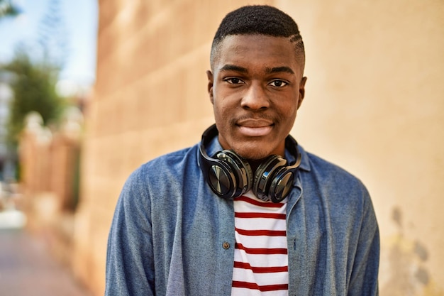 Joven afroamericano con expresión relajada usando auriculares en la ciudad.