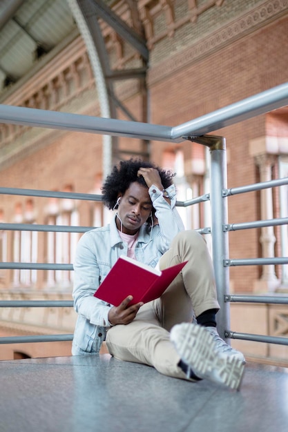 Joven afroamericano con peinado afro disfrutando de un momento tranquilo leyendo un libro Espacio para texto