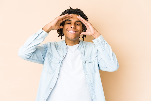 Joven afroamericano rasta ríe con alegría manteniendo las manos en la cabeza. Concepto de felicidad.