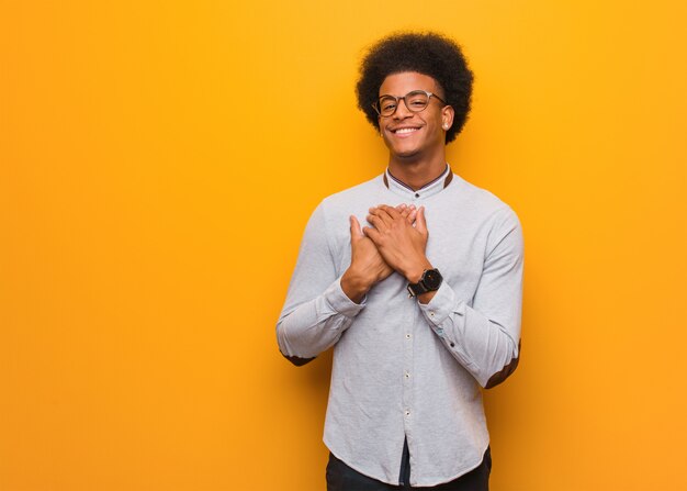 Joven afroamericano sobre una pared naranja haciendo un gesto romántico