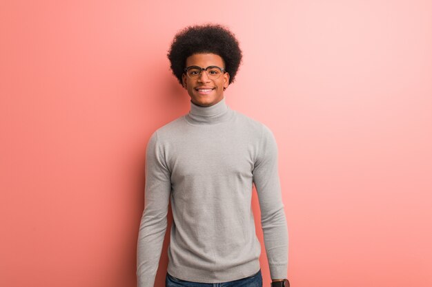 Joven afroamericano sobre una pared rosa alegre con una gran sonrisa