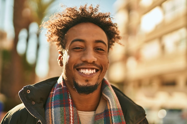 Joven afroamericano sonriendo feliz de pie en la ciudad