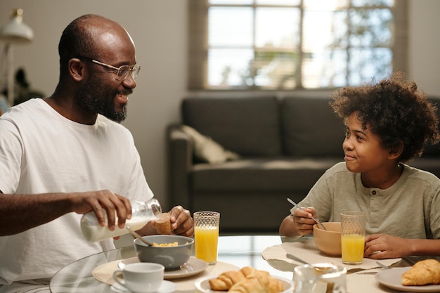 Joven afroamericano y su lindo hijo desayunando juntos