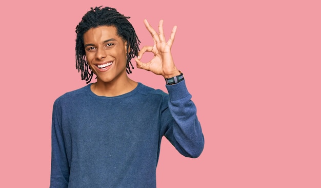 Joven afroamericano con suéter de invierno casual sonriendo positivamente haciendo bien el signo con la mano y los dedos. expresión exitosa.