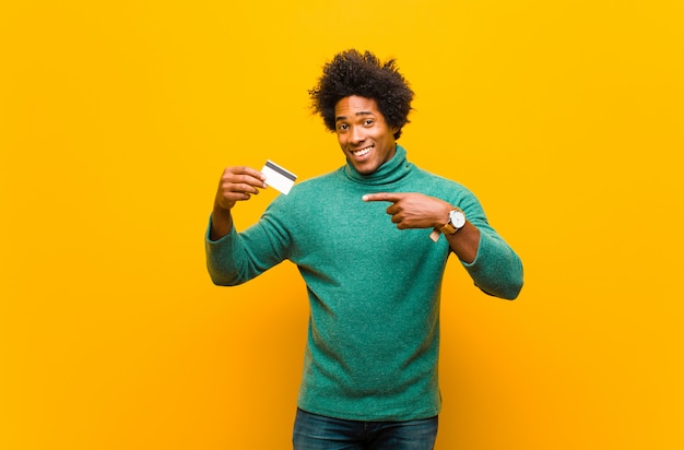 Joven afroamericano con una tarjeta de crédito naranja