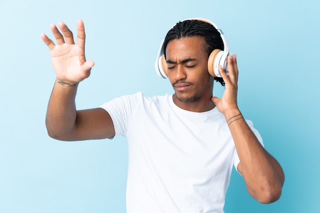 Joven afroamericano con trenzas en azul escuchando música y bailando